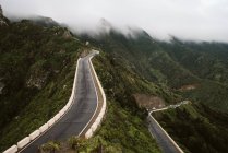 Two asphalt roads going through mountain ridge on wonderful misty day in majestic countryside — Stock Photo