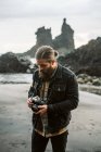 Bearded photographer standing near sea — Stock Photo