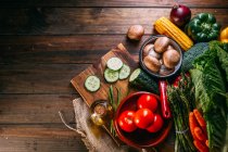 Асортимент свіжих сирих овочів і посуду на дерев'яному кухонному столі — стокове фото