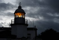 Shining lighthouse against cloudy sky — Stock Photo