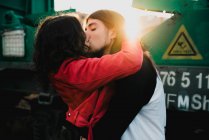 Langhaariger Mann umarmt und küsst Frau in Bahnnähe — Stockfoto