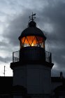 Shining lighthouse against cloudy sky — Stock Photo