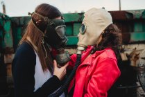 Seitenansicht junger Hipster in trendiger Kleidung und Atemschutzmasken, die in der Nähe von Altbauten stehen — Stockfoto