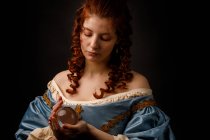 Barockfrau blickt herab, während sie magische Glaskugel in der Hand hält. — Stockfoto