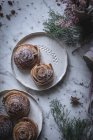 Top view of plates with cinnamon rolls on table decorated with herbs and spices. — Stock Photo