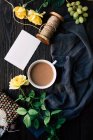 Зверху красиві жовті троянди і порожня нота біля чашки свіжої кави на дерев'яній стільниці . — стокове фото