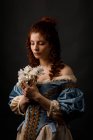 Femme baroque aux yeux fermés tenant des fleurs . — Photo de stock