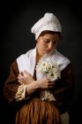 Medieval maid holding flowers on black background. — Stock Photo