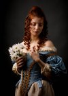 Красива жінка в середньовічній сукні з закритими очима тримає купу білих квітів . — стокове фото