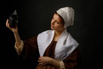 Schöne Frau im einfachen mittelalterlichen Kleid mit alter Fotokamera für ein Selfie. — Stockfoto