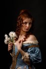 Schöne Frau in mittelalterlicher Kleidung mit Gänseblümchen und Blick in die Kamera. — Stockfoto