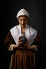 Medieval woman using vintage photo camera on black background. — Stock Photo
