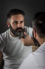 Expressive barber cutting beard — Stock Photo
