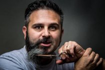 Expressive barber cutting beard — Stock Photo