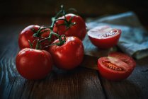 Fechar grupo de tomates maduros molhados colocados perto de guardanapo na mesa de madeira serrada — Fotografia de Stock