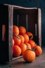 Свежие апельсины в перевернутой деревянной коробке — стоковое фото