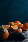 Frische ganze und geschnittene Orangen auf dunklem Holzgrund — Stockfoto