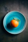 Fresh orange in blue plate on dark background — Stock Photo