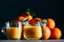 Jugo de naranja en vasos sobre fondo oscuro - foto de stock