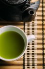 Nahaufnahme der Tasse mit frischem grünen Matcha-Tee und Vintage-Kanne auf dem Tisch. — Stockfoto