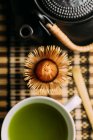 Close-up of cup with fresh green matcha tea, vintage pot and bamboo whisk preparing tool on table. — Stock Photo