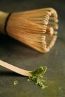 Close-up of green matcha tea powder on little spoon and bamboo whisk. — Stock Photo