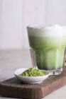 Bebida de latte Matcha en vidrio y polvo de matcha verde en tablero de madera, primer plano
. - foto de stock