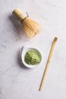 Polvo de té matcha verde y batidor de bambú con cuchara en la mesa . - foto de stock