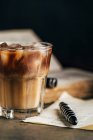 Cold espresso coffee in glass glass on dark grunge background with old book — Stock Photo