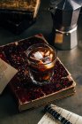 Café espresso frío en vidrio sobre fondo grunge oscuro con libro antiguo - foto de stock