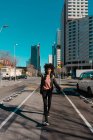 Mujer con pelo afro caminando por las calles de una gran ciudad - foto de stock