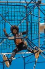 Woman with afro hair climbing by children's attractions in a park — Stock Photo