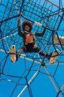 Mujer con cabello afro trepando por atracciones infantiles en un parque - foto de stock