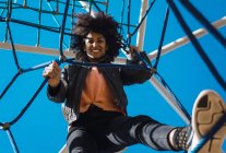Woman with afro hair climbing by children's attractions in a park — Stock Photo