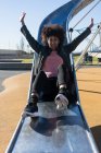 Woman with afro hair jumping down a slide with great joy — Stock Photo