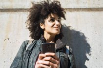 Портрет черной женщины с афроволосами, опирающейся на стену на улице — стоковое фото