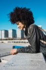 Portrait of black woman with afro hair leaning on a wall in the street — Stock Photo