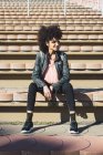 Black woman with afro hair sitting on the steps of a stadium — Stock Photo