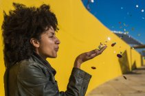 Schwarze Frau mit Afrohaaren wirft Konfetti, um einen ganz besonderen Tag zu feiern — Stockfoto