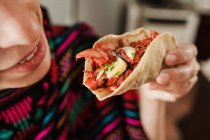 Unrecognizable female holding fresh tortilla with sliced meat on blurred background of room — Stock Photo