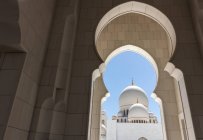 Vista del fantástico palacio blanco a través de arcos increíbles en un día soleado en Emiratos Árabes Unidos - foto de stock