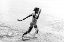 На вигляд афроамериканського підлітка з іграшками, що пливуть морем на ямайці. — стокове фото