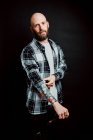 Бородатий безшерстий хіпстер у сорочці з татуюваннями на руках на чорному тлі — стокове фото