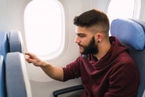 Barbudo cara usando smartphone no avião — Fotografia de Stock