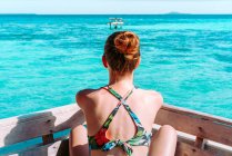 Visão traseira da senhora de maiô e óculos de sol sentados no assento perto do mar azul na Jamaica — Fotografia de Stock