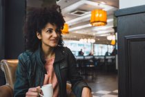 Femme noire aux cheveux afro buvant un café dans un café — Photo de stock