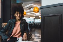 Чорна жінка з афро волоссям п'є каву в кав'ярні — стокове фото