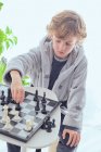 Boy holding figure on chess board — Stock Photo