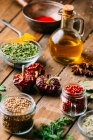 Assorted spices and herbs and bottle of oil placed on wooden tabletop — Stock Photo