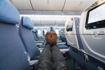 Legs of anonymous man in stylish pants and shoes lying on comfortable seats inside modern aircraft — Stock Photo